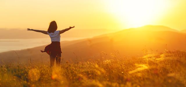 Happy Woman Standing With Her Back on Sunset in Nature With Open Hands